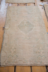 Distressed vintage Oushak rug showing even wear across its faded cream and celadon green patterns.