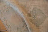 Distressed Oushak rug texture, cream pile with subtle celadon green designs.