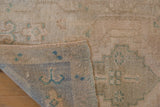 Distressed Oushak rug detail: worn pile and visible hand-knotted reverse, beige and celadon.