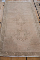 Angled perspective of the distressed Oushak rug mat showing its full length and muted medallion.
