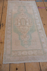 Distressed Turkish Oushak runner detail, geometric finials in seafoam green and cream.