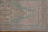 Distressed Oushak rug's border with seafoam green and beige, showing original selvage.