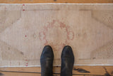 Distressed Oushak rug with subtle roundel medallion, pale cranberry and ivory tones, even wear.