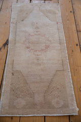 Distressed Oushak rug corner displays original selvage, faint stepped pattern, and neutral tones.