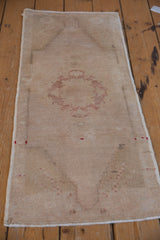 Distressed Oushak rug corner with pale cranberry pinwheel pattern and original selvage.