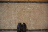 Distressed texture of a vintage Oushak rug pile, featuring beige, greige, and light worn areas.