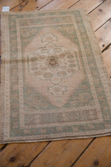 Abrashed ivory field of distressed Oushak rug showing its soft seafoam green patterns.