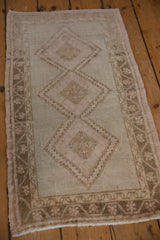Distressed Oushak rug with worn diamond medallion and meandering vine border.