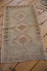 Distressed Oushak rug: triple diamond medallion, meandering vine border, antique ivory, pale seafoam green.
