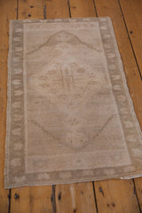 Vintage distressed Oushak rug corner, revealing soft sand tones, even wear, and intact selvage.