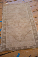 Distressed Oushak rug side: beige and sand tones, muted border pattern, short pile, and intact selvage.
