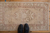 Vintage distressed Oushak rug corner, highlighting pale cream and rose floral motifs.