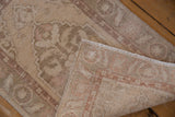 Distressed Oushak rug, a folded corner showing the hand-knotted foundation and intact selvage.