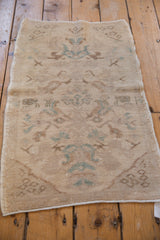 Distressed Oushak rug corner showing faint seeded bud motifs in pale turquoise and beige.