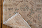 Folded corner of vintage Oushak rug mat showing distressed pile texture and hand-knotted foundation.
