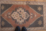 Dusty copper and charcoal distressed Oushak rug with geometric medallion.