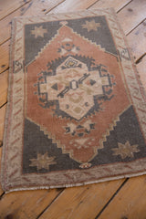 Distressed Oushak rug with central starburst motif and finial, featuring dusty copper and charcoal.