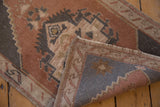 Distressed Oushak rug, dusty copper and charcoal geometric pile, revealing wear and faint foundation.