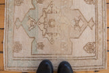 Faded ivory and beige distressed Oushak rug with soft seafoam medallion design.