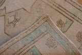 Distressed ivory Oushak rug pile with visible hand-knotted seafoam green woven back.
