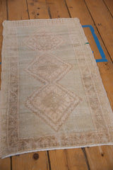 Distressed pile texture of a vintage Oushak rug with faded hook and latch relief in beige and seafoam.