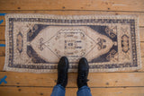 Distressed Oushak rug with ivory field, navy stylized medallion, and subtle brown accents.