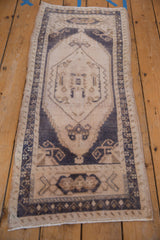 Distressed vintage Oushak rug runner, faded ivory field with muted navy medallion.