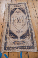 Detailed view of the distressed Oushak runner's intact side selvage, short pile, and navy border.