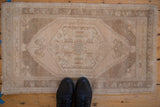 Vintage distressed Oushak rug mat, worn texture, hexagonal medallion in beige, sand tones.