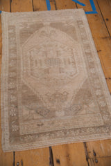 Distressed pile texture and muted beige tones at the vintage Oushak rug's corner.