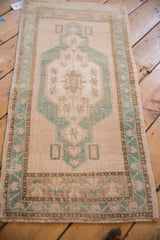 Distressed vintage Oushak rug detail, highlighting jade green floral border and soft beige field with natural wear.