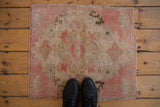Distressed Turkish Oushak rug showing even wear across pink, blue, and bronze stylized floral motifs.