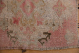 Close-up of distressed Oushak rug pile showing pink tones, visible wear, and original selvage.