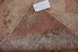 Folded distressed Oushak rug showing original side cord selvages and foundation with even wear.