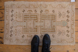 Distressed Oushak mat with double medallion, pinwheel florals, and soft cream, bronze tones.