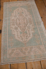 Distressed Oushak rug with geometric vinery, seafoam green, and visible faint foundation.