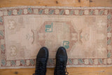 Distressed Oushak runner showcasing muted cream, dusty copper, and pale turquoise geometric patterns.