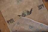 Distressed Turkish Oushak rug showing low pile, sand colors, and woven back foundation.