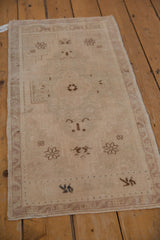 Subtle beige floral and geometric motifs with distressed pile on a vintage Oushak rug.