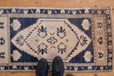 Distressed Oushak runner with ivory field, primitive palmettes and serrated navy outlines.