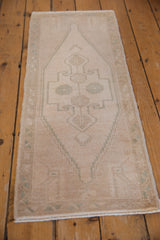 Distressed vintage Oushak runner with even wear and subtle seafoam green floral motifs.