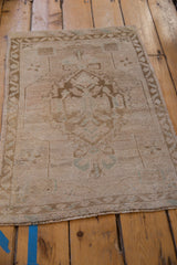Vintage distressed Oushak rug corner, showing pale seafoam green and dusty bronze vine border.