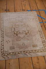 Distressed vintage Oushak rug corner, showing meandering vine border in beige and ivory.