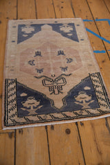 Angled view of a vintage Oushak mat's charcoal corner spandrels and short, distressed pile.