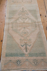 Distressed Oushak rug border pattern with cream and seafoam green germinating plants.