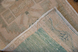 Close-up of vintage Oushak rug's hand knotted foundation, side selvage, and distressed seafoam green pile.