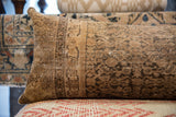 Antique Persian rug fragment lumbar pillow, detailing its worn texture and faded charcoal patterns.