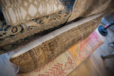 Antique Persian rug fragment pillow edge showing worn pile and beige linen backing.