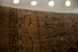 Close-up of antique Persian rug fragment showing worn hand-knotted pile and visible foundation.