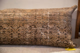 Antique Persian rug fragment pillow showing low pile, visible foundation, and worn beige and charcoal pattern.